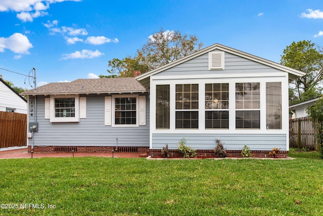 view of front of property featuring roof with shingles, fence, and a front yard