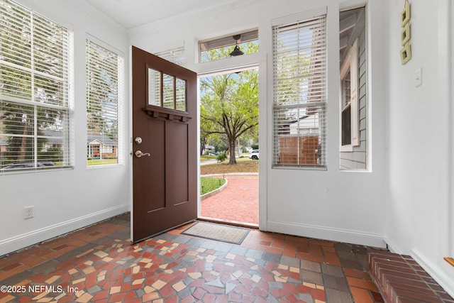 entrance foyer featuring plenty of natural light, baseboards, and crown molding