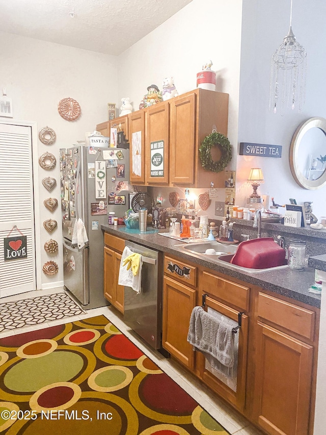 kitchen with stainless steel appliances, dark countertops, brown cabinets, and a sink