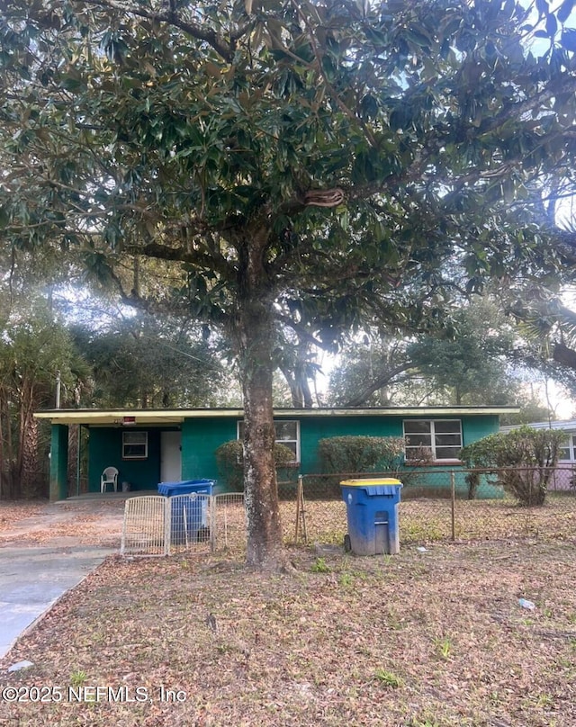 view of front of property featuring a fenced front yard, an attached carport, and driveway