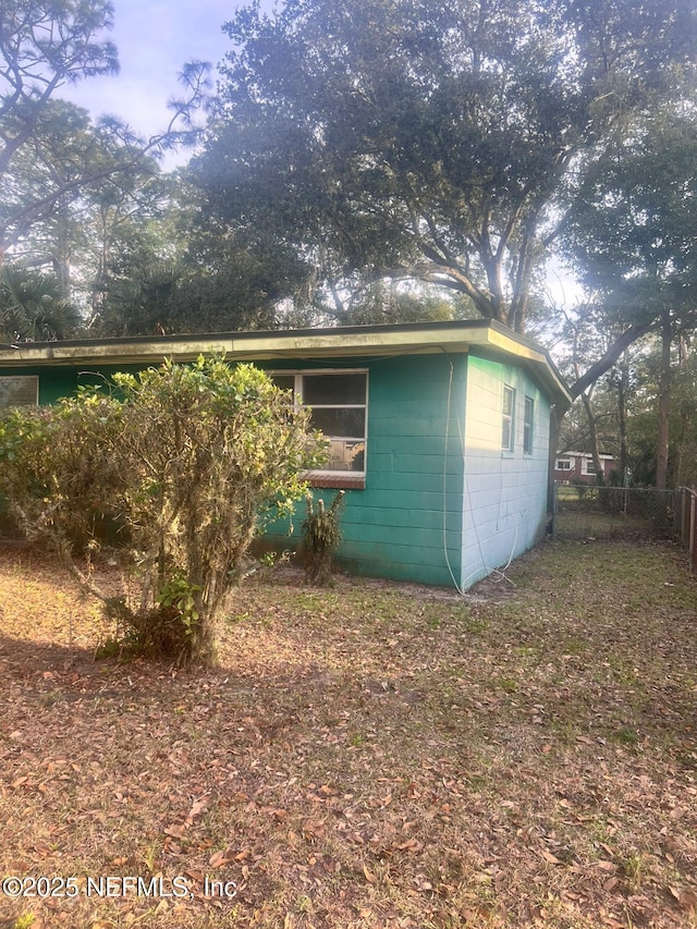 view of side of property featuring concrete block siding and fence