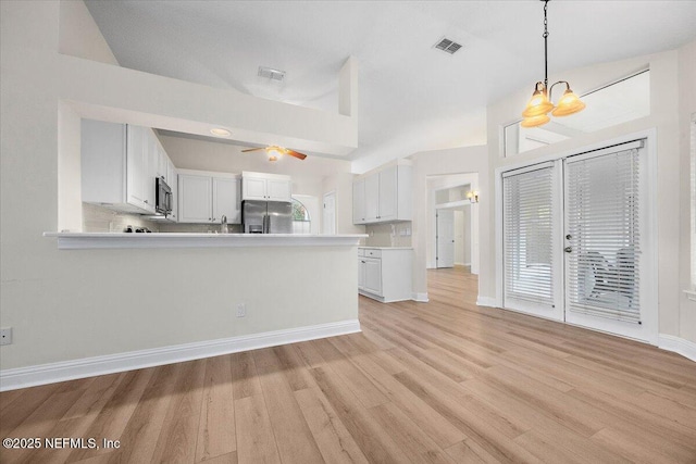 kitchen with light countertops, stainless steel fridge, visible vents, and white cabinetry