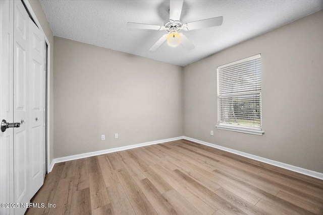 unfurnished bedroom featuring a textured ceiling, a closet, light wood-type flooring, and baseboards