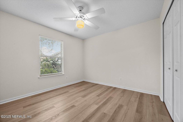 unfurnished bedroom with a textured ceiling, a closet, light wood-style flooring, and baseboards