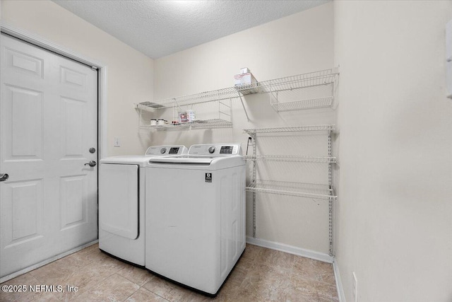 laundry area with laundry area, washing machine and dryer, and a textured ceiling