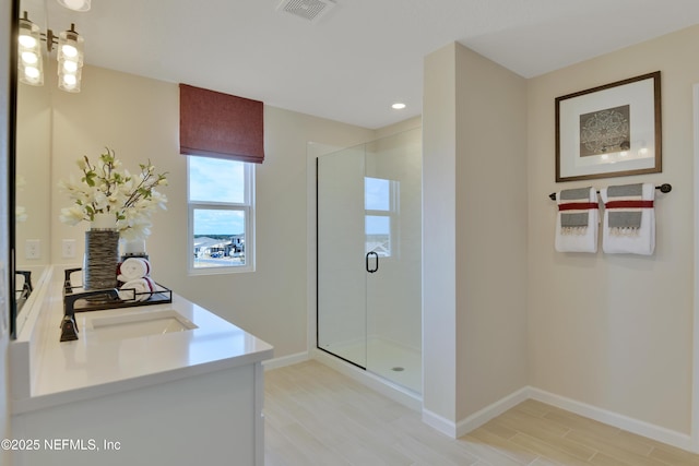 full bathroom featuring wood finished floors, a stall shower, vanity, and visible vents