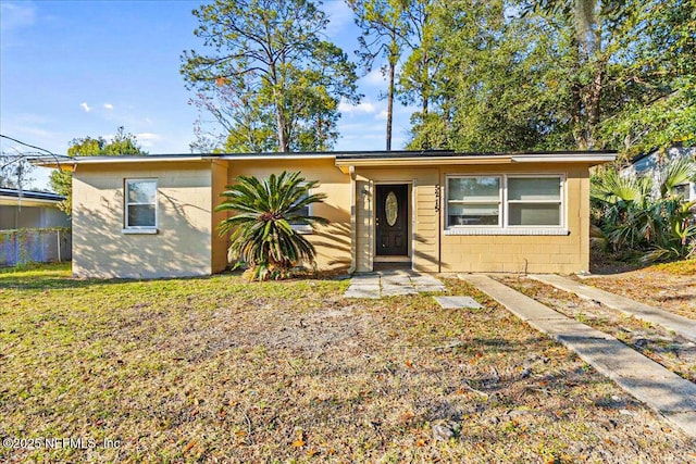 view of front facade with concrete block siding and a front lawn