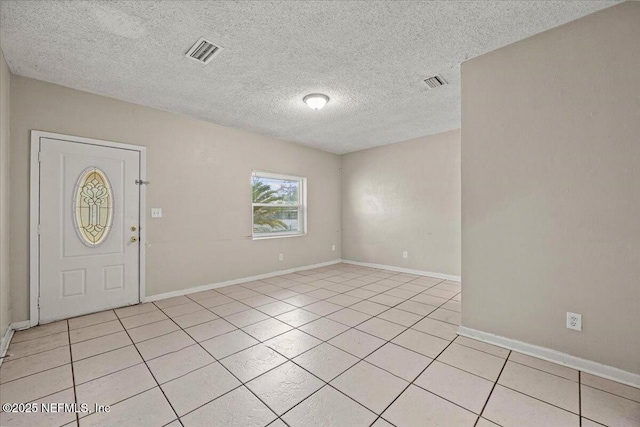 entrance foyer featuring light tile patterned floors, a textured ceiling, visible vents, and baseboards