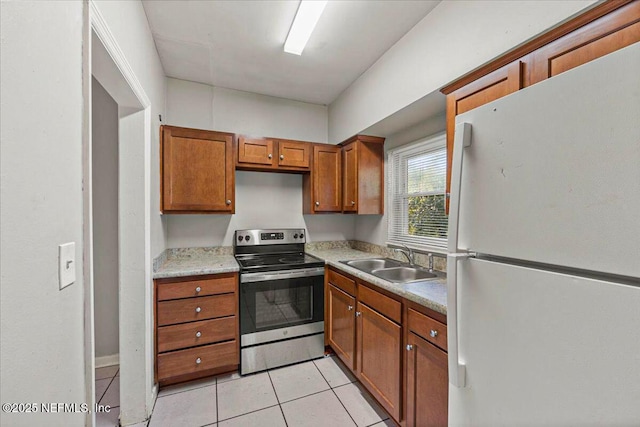 kitchen featuring stainless steel electric range oven, brown cabinets, freestanding refrigerator, light countertops, and a sink