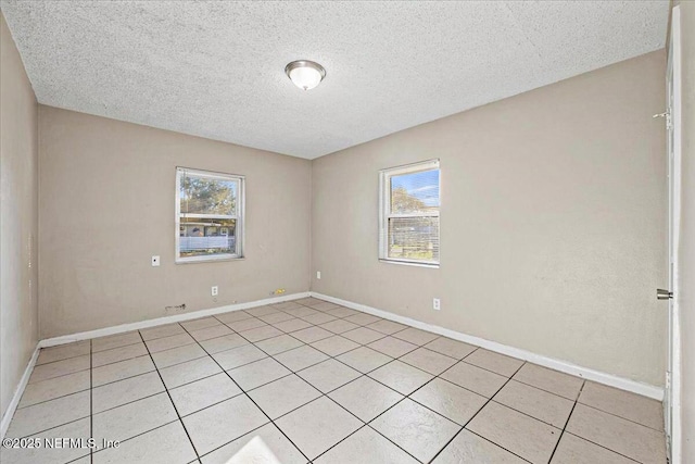 spare room with a textured ceiling and baseboards