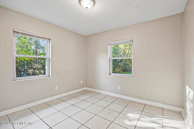 empty room with light tile patterned floors and baseboards