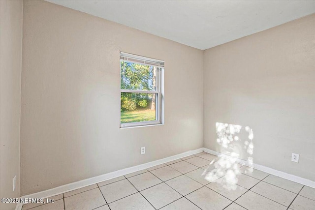 spare room featuring light tile patterned floors and baseboards