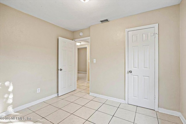 unfurnished bedroom featuring light tile patterned floors, visible vents, and baseboards