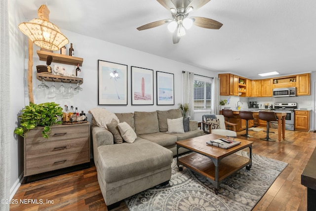 living area with dark wood-style flooring, ceiling fan, and baseboards