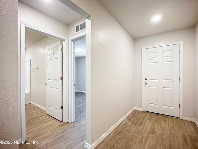 hallway with baseboards, visible vents, and light wood-style floors