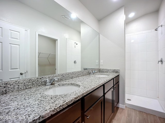 bathroom featuring a tile shower, wood finished floors, and a sink