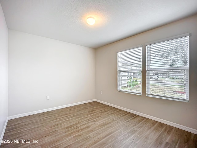 spare room featuring a textured ceiling, baseboards, and wood finished floors