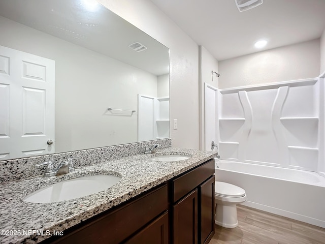 full bathroom featuring toilet, double vanity, a sink, and wood finished floors