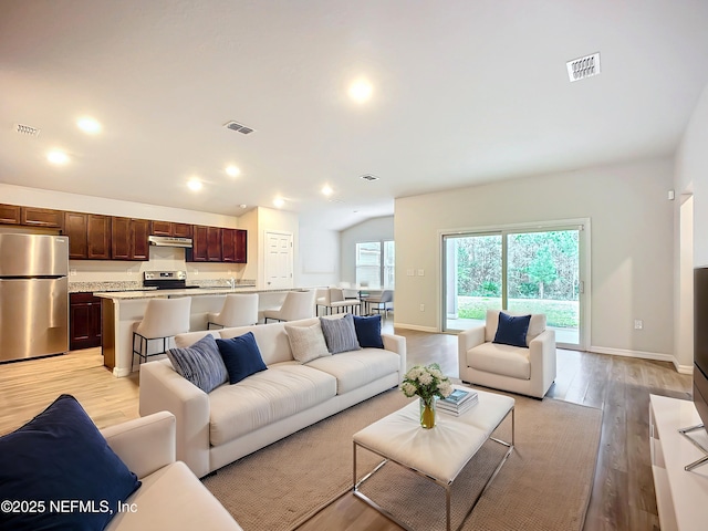 living room featuring light wood-type flooring, visible vents, and recessed lighting