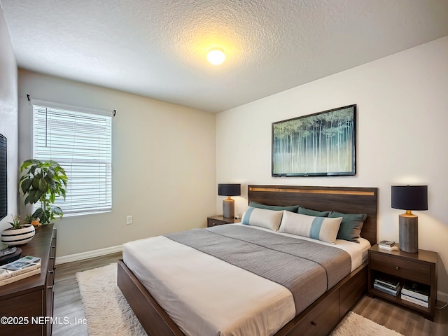 bedroom with a textured ceiling, wood finished floors, and baseboards