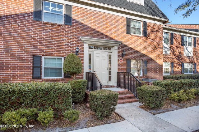 property entrance featuring brick siding and roof with shingles