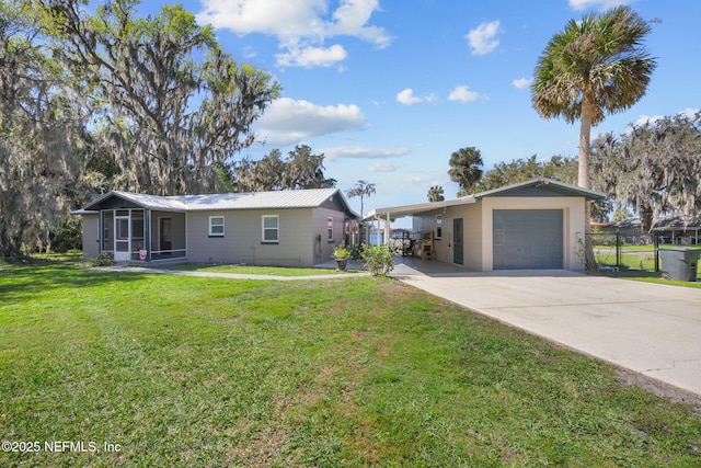 ranch-style house featuring concrete driveway, a sunroom, metal roof, fence, and a front lawn