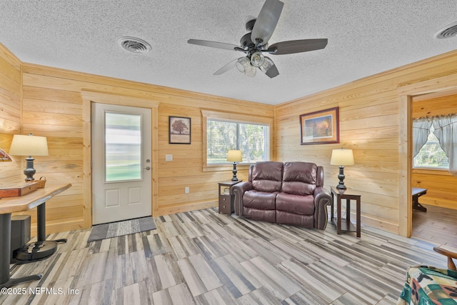 living room with wood walls, visible vents, and a textured ceiling