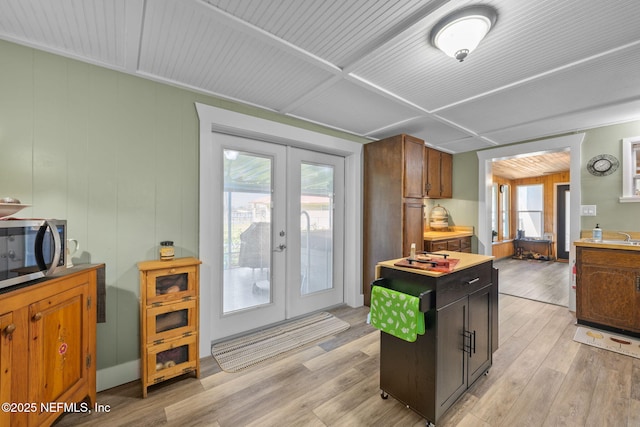 kitchen featuring light wood-style floors, light countertops, french doors, and stainless steel microwave