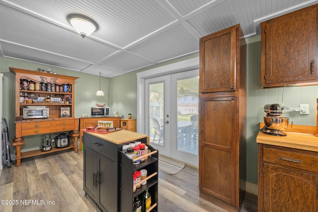 kitchen featuring pendant lighting, french doors, open shelves, butcher block countertops, and light wood-type flooring