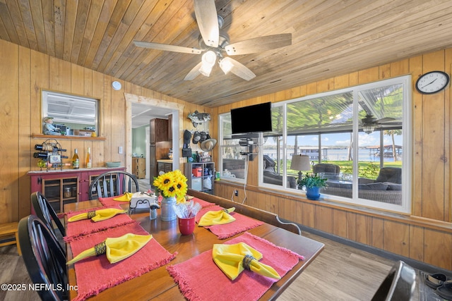 dining room with wood finished floors, wood ceiling, and wooden walls