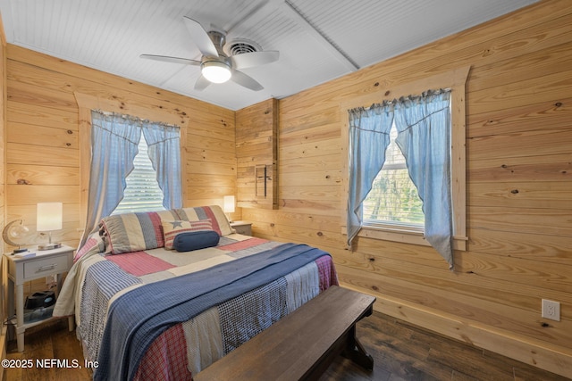 bedroom with wood walls, dark wood finished floors, and a ceiling fan