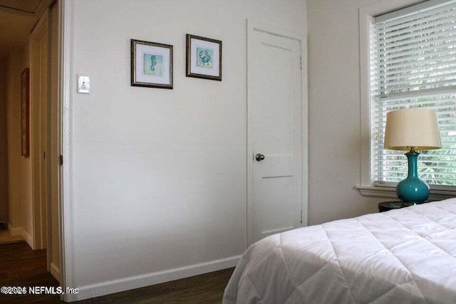 bedroom with dark wood-type flooring and baseboards