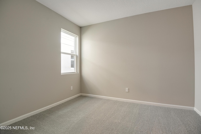 carpeted empty room featuring baseboards