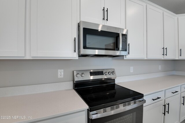 kitchen with stainless steel appliances, light countertops, and white cabinets