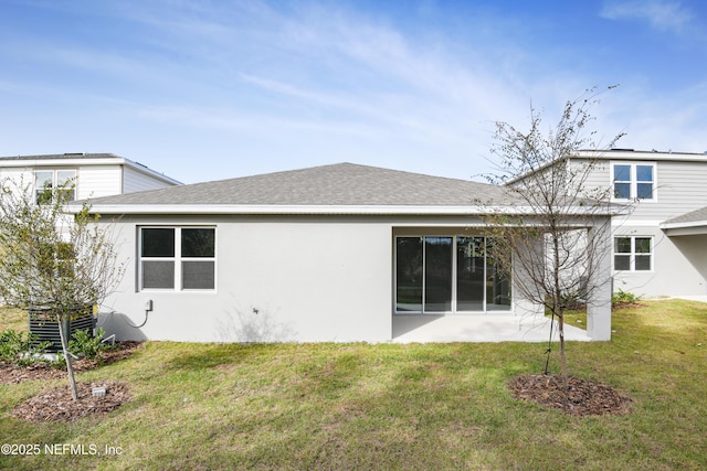 rear view of property featuring roof with shingles, a lawn, and stucco siding