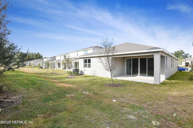 rear view of property featuring roof with shingles, a lawn, and a patio