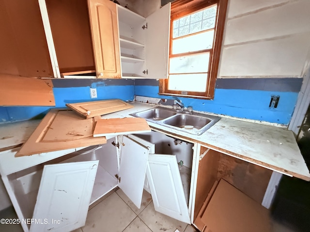 kitchen featuring light tile patterned floors, light countertops, open shelves, and a sink