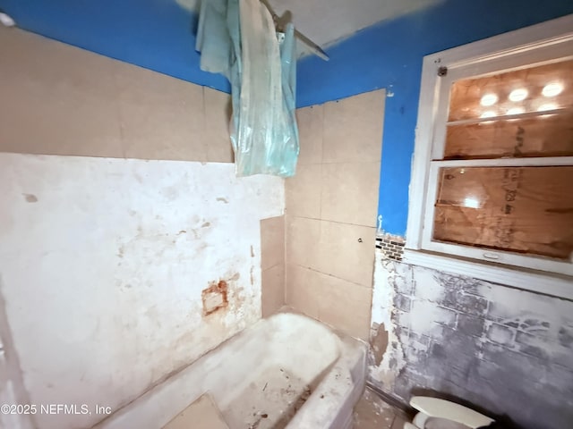 bathroom with tile walls and shower / bathtub combination