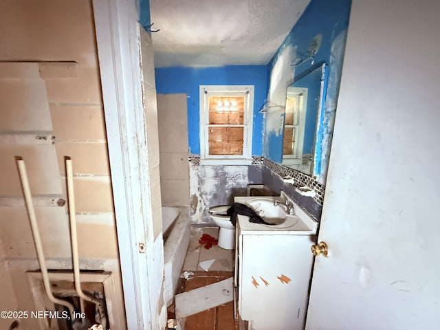 full bathroom featuring toilet, a washtub, vanity, and tile walls