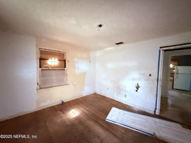 spare room with visible vents, baseboards, and wood finished floors