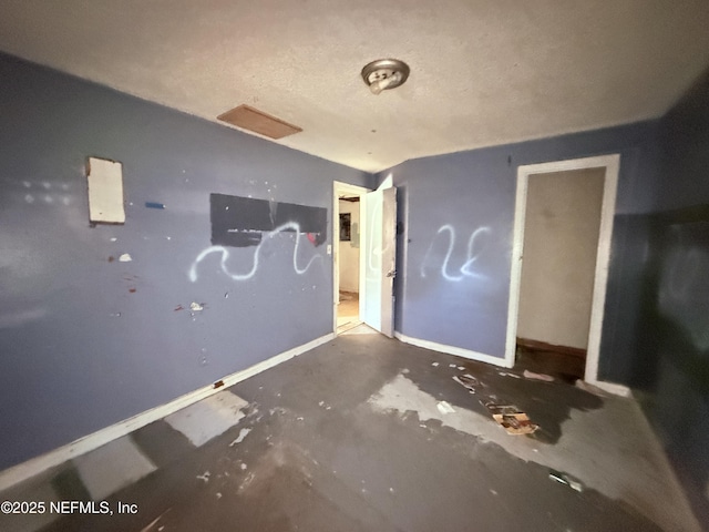 interior space featuring a textured ceiling and baseboards