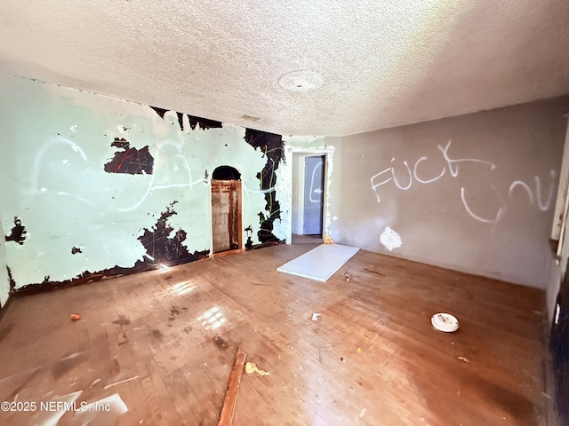 unfurnished room featuring a textured ceiling and wood finished floors