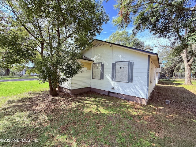 view of side of property with crawl space and a lawn