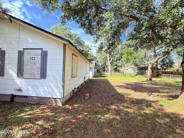 view of home's exterior with crawl space, a fenced backyard, an outdoor structure, and a storage unit