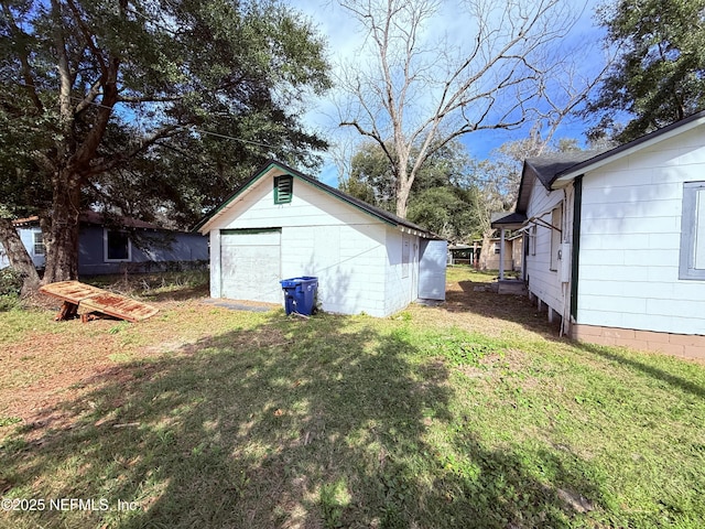 view of yard featuring an outbuilding, a detached garage, and driveway