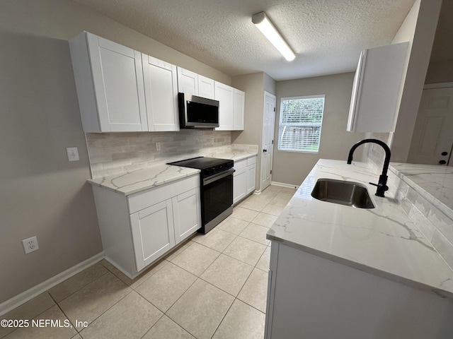 kitchen featuring black / electric stove, light stone counters, a sink, white cabinets, and stainless steel microwave