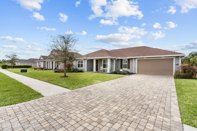 93322 Sandown Dr, Fernandina Beach, FL 32034 - ranch-style home featuring decorative driveway, a front yard, an attached garage, a shingled roof, and a porch