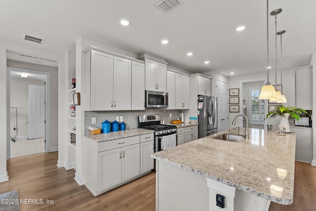93322 Sandown Dr, Fernandina Beach, FL 32034 - kitchen featuring appliances with stainless steel finishes, a sink, tasteful backsplash, an island with sink, and light wood-style floors