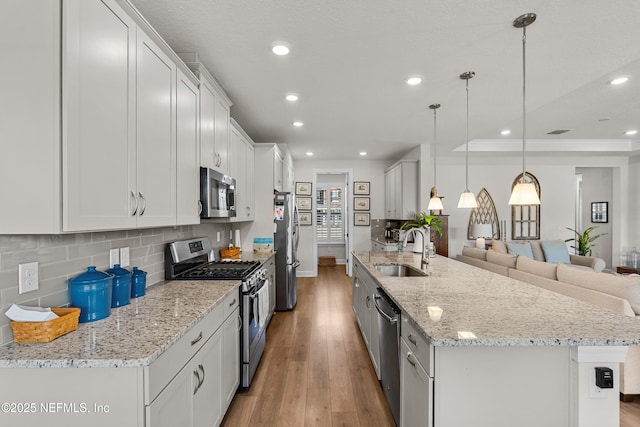93322 Sandown Dr, Fernandina Beach, FL 32034 - kitchen featuring stainless steel appliances, a sink, light wood-type flooring, open floor plan, and decorative backsplash