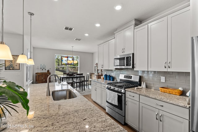 93322 Sandown Dr, Fernandina Beach, FL 32034 - kitchen featuring appliances with stainless steel finishes, a sink, tasteful backsplash, light stone countertops, and white cabinets